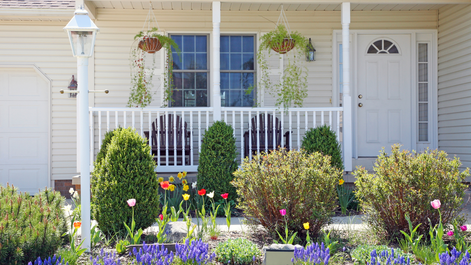 Spring home exterior with front porch, blooming flowers, and landscaped yard representing April housing market trends