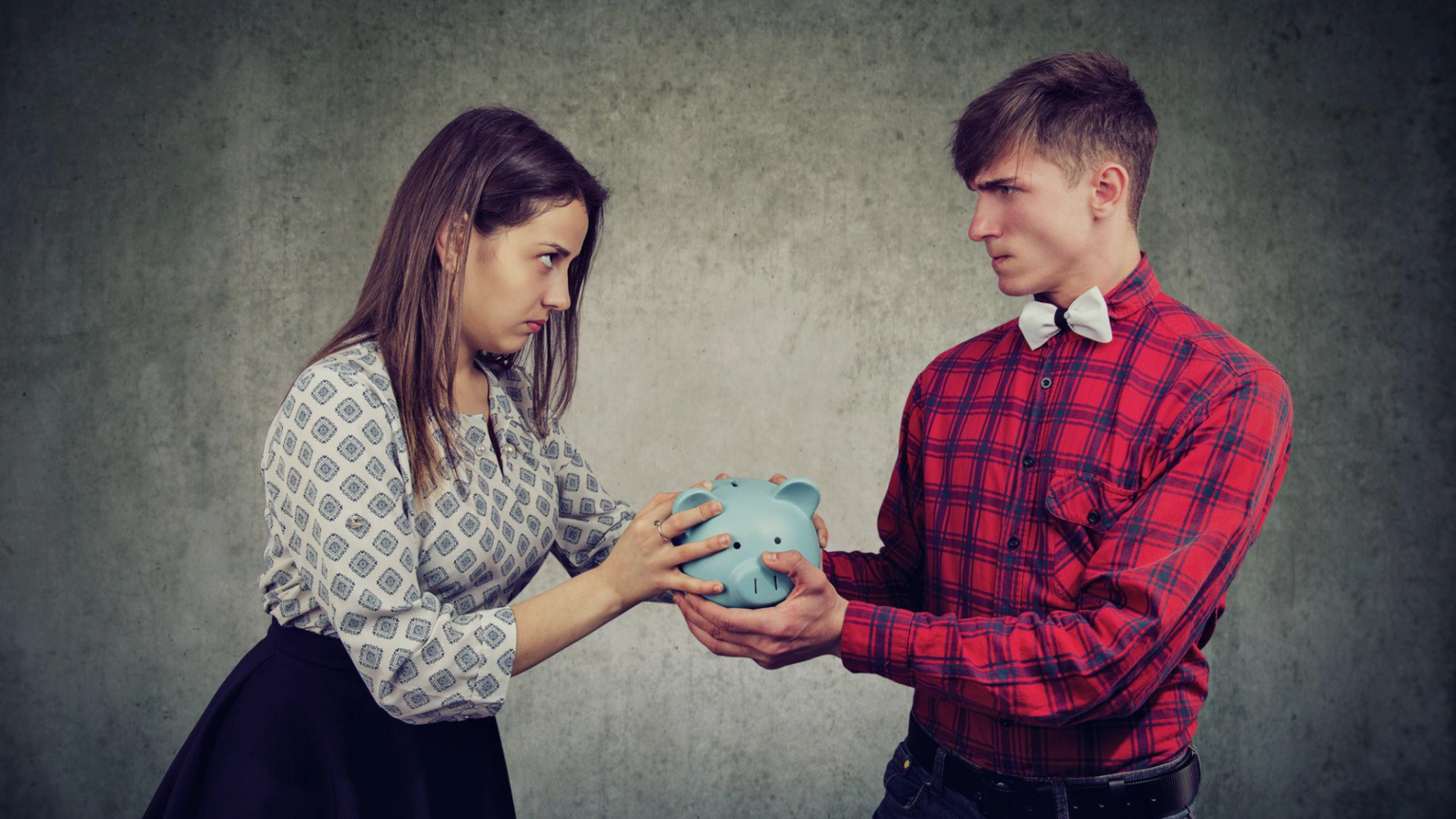 Man and woman sitting apart with a piggy bank between them, symbolizing financial division and insurance or asset disputes during divorce
